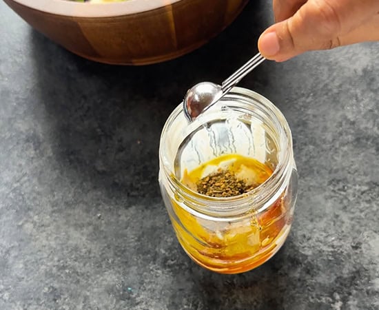 adding seasoning to salad dressing