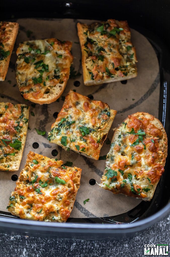seven pieces of garlic bread arranged in an air fryer