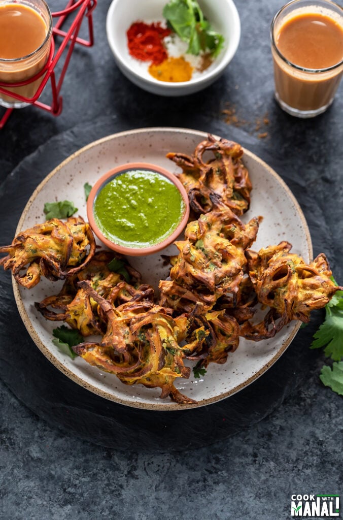 onion pakoda in a plate with a bowl of cilantro chutney