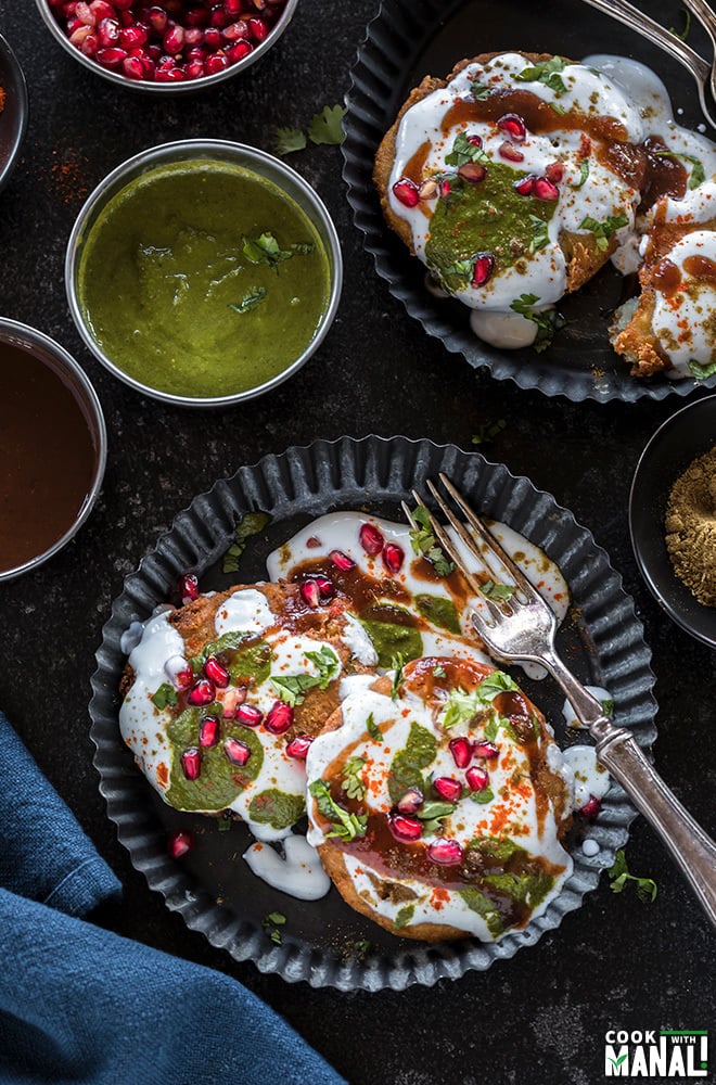 plate of aloo tikki with smalls bowls of chutney, spices all around