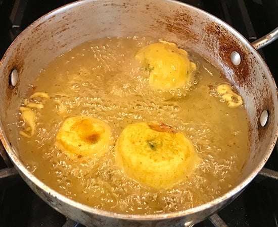 3 pieces of batana vada being fried in oil