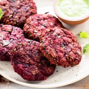 beetroot tikkis arranged on a plate with bowl of chutney on the side