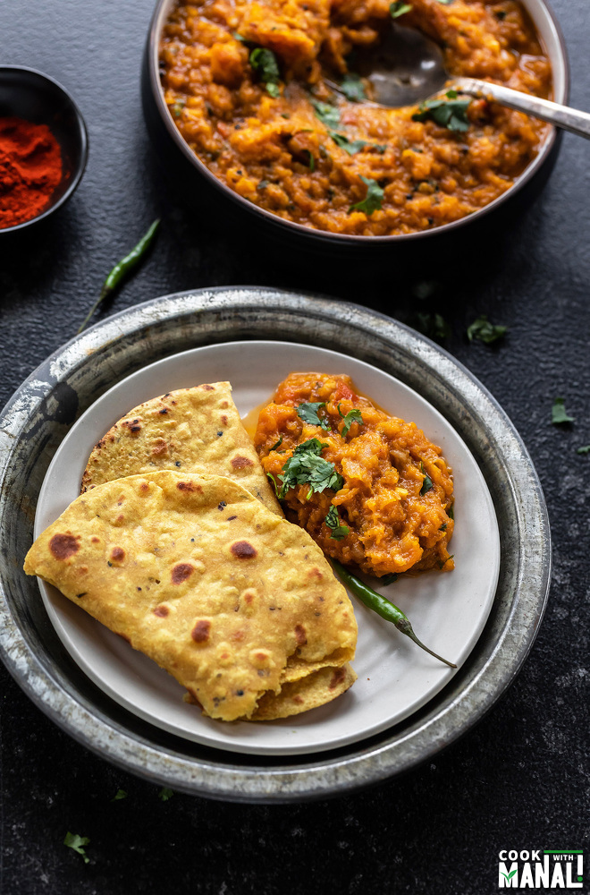 butternut squash bharta served with flatbread in a plate with a green chili placed on the side