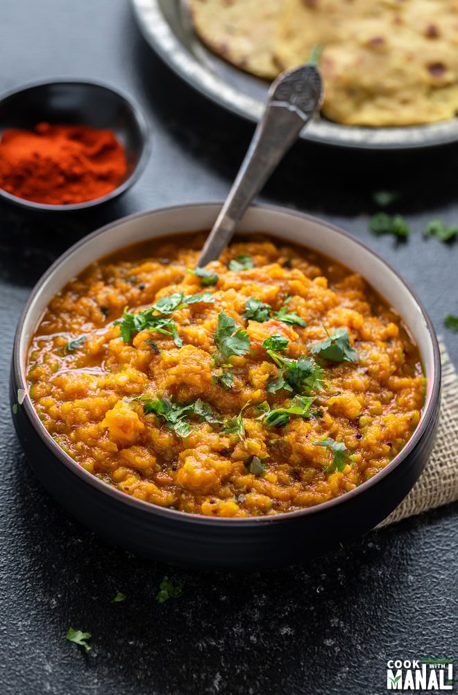 mashed butternut squash in a bowl with some flatbreads placed in the background