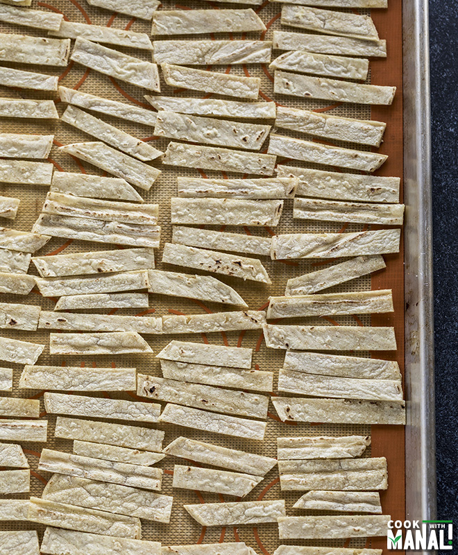 corn tortilla strips arranged on a baking tray in a single line