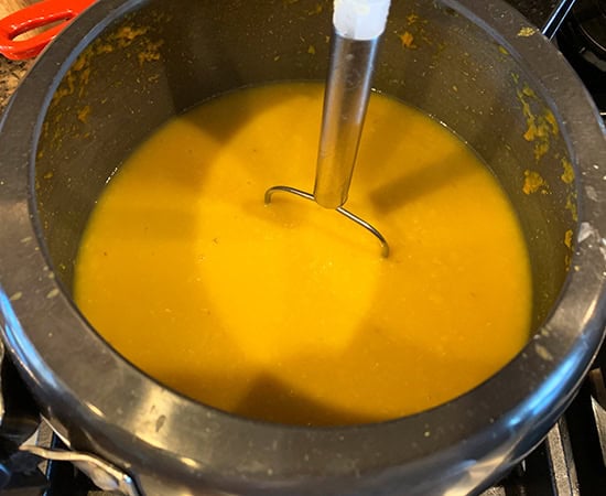 dai in pressure cooked being mashed with a potato masher