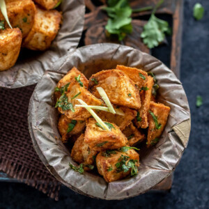 crispy fried potatoes served in a bowl and garnished with ginger juliennes and cilantro