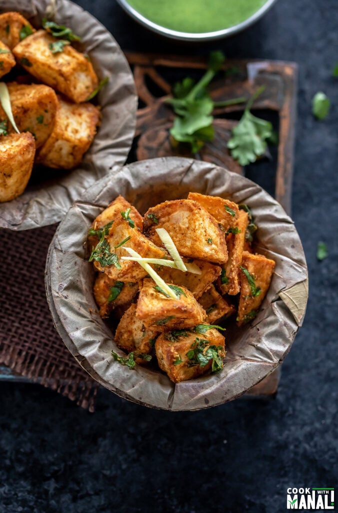 crispy fried potatoes served in a bowl and garnished with ginger juliennes and cilantro