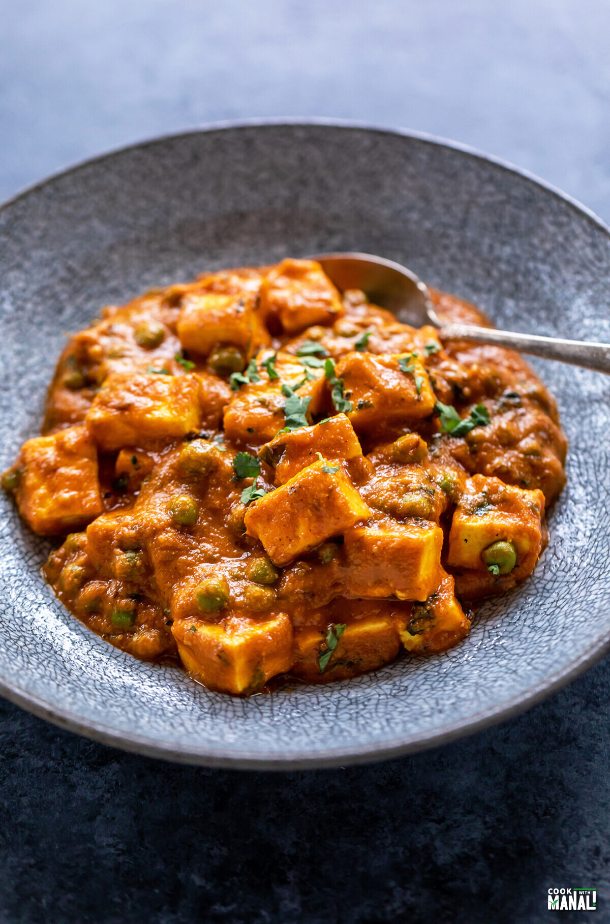 matar paneer served in a bowl with spoon on the side