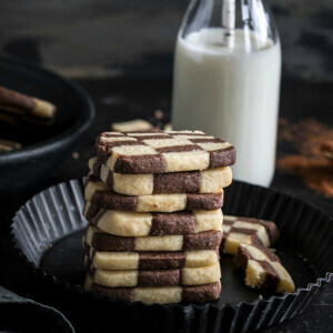 stack of checkerboard cookies with a bottle of milk in the background