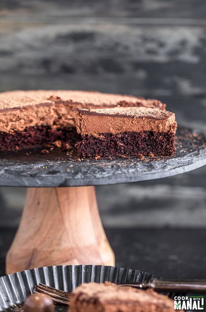 slice of eggless chocolate mousse cake placed on a black cake stand with another slice placed in a plate