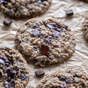 oatmeal chocolate chunk cookies on parchment paper with melting chocolate on top