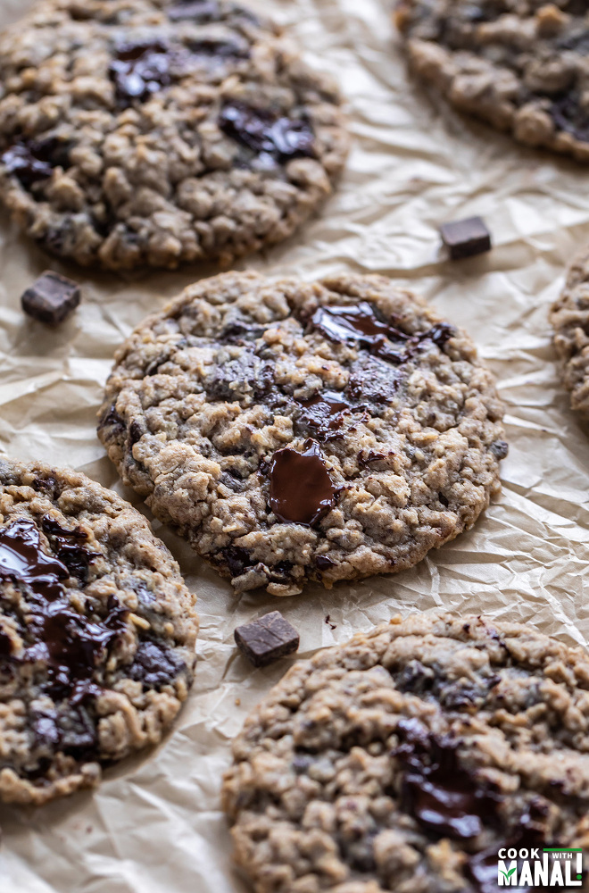 oatmeal chocolate chunk cookies on parchment paper with melting chocolate on top