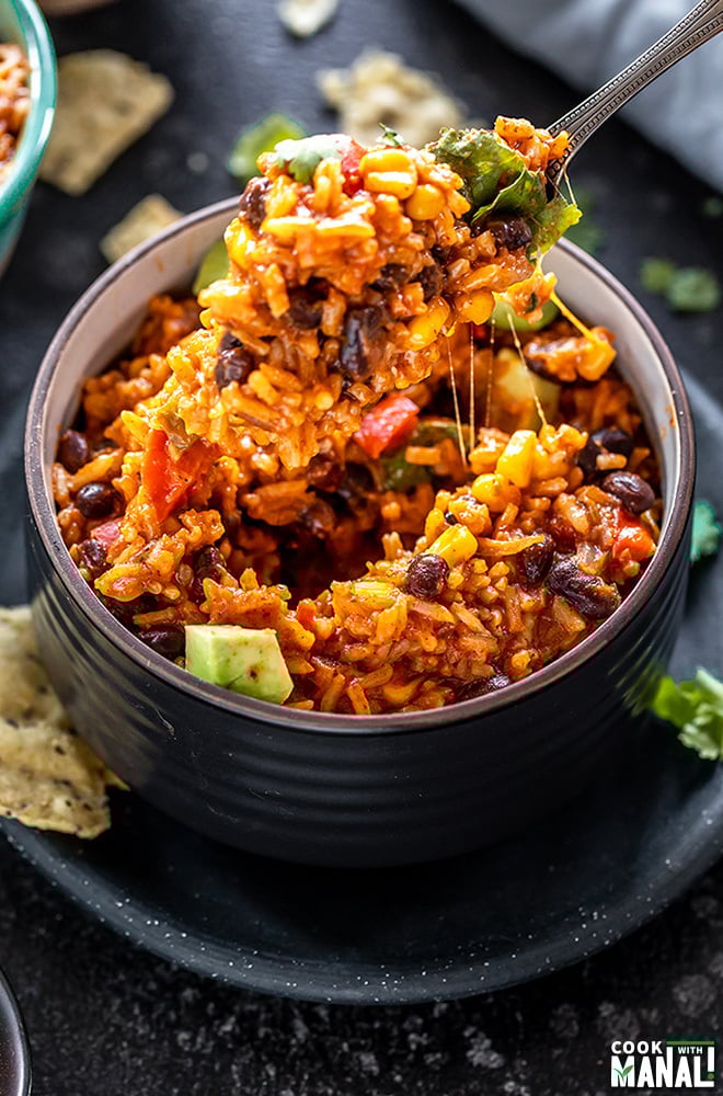 enchilada rice in a black bowl with a fork pulling out rice from the bowl