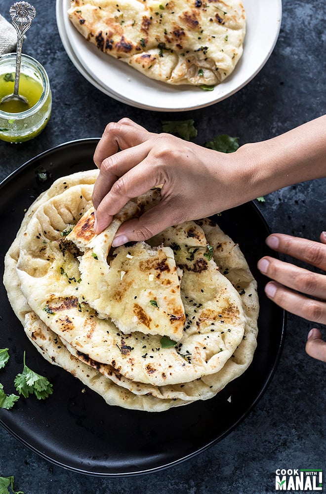 pair of hands taking a bite off homemade garlic naan