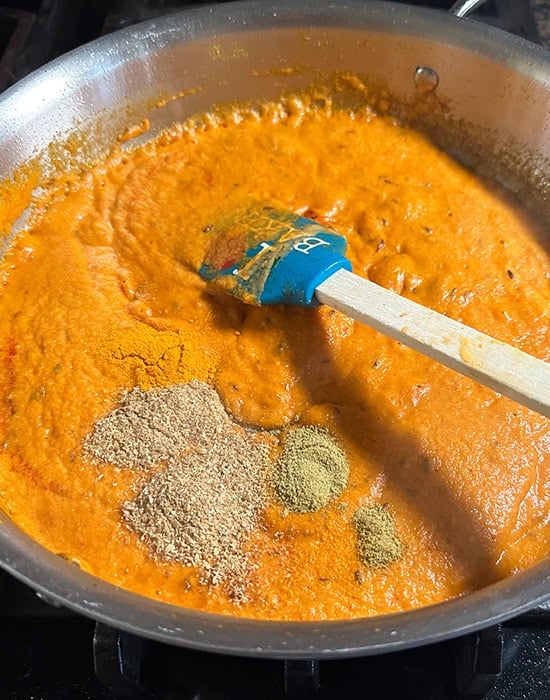 ground spices being added to a curry