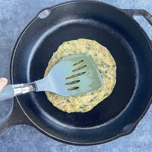a spatula pressing down a paratha