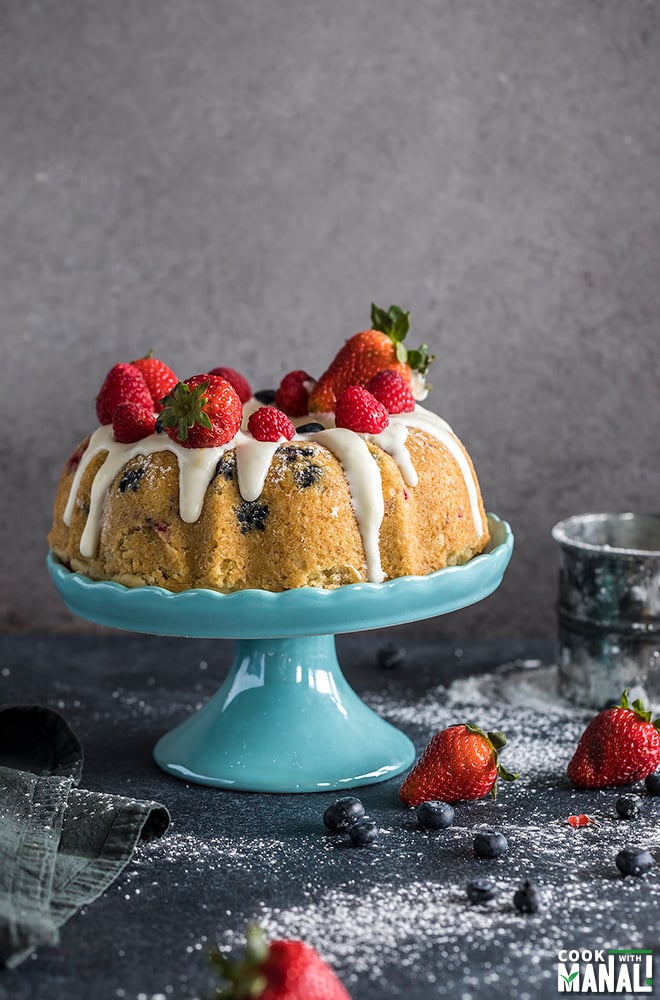 instant pot berry vanilla cake topped with fresh berries and placed on a blue cake stand
