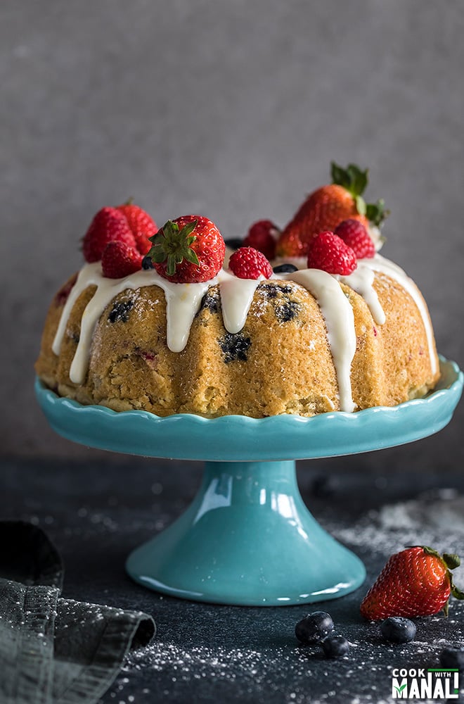 instant pot berry vanilla cake topped with fresh berries and placed on a blue cake stand