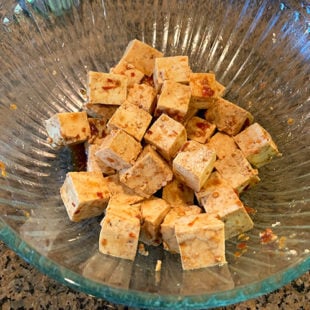 marinated tofu cubes in a glass bowl