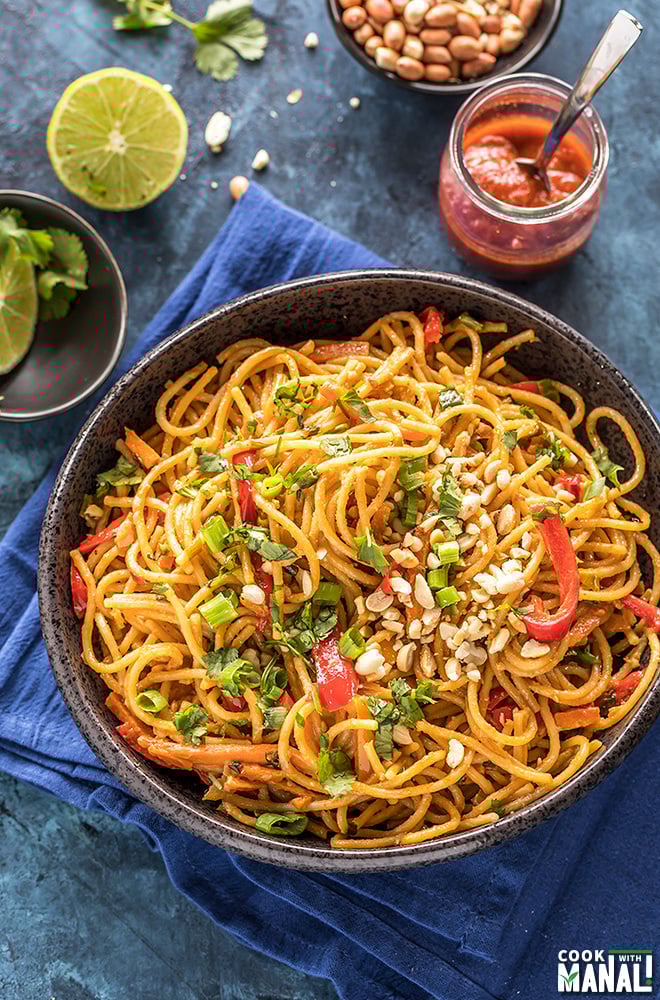 instant pot thai peanut noodles served in a black bowl with lime and hot sauce in the background