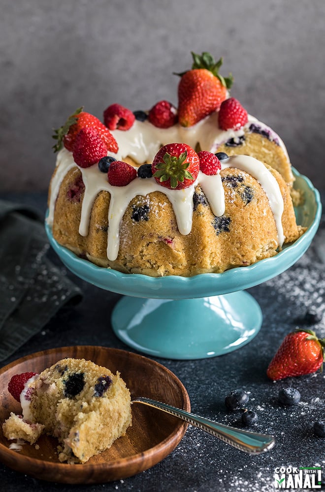 instant pot berry vanilla cake topped with fresh berries and placed on a blue cake stand