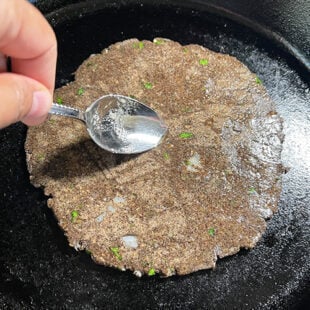 oil being applied to a flatbread on a skillet