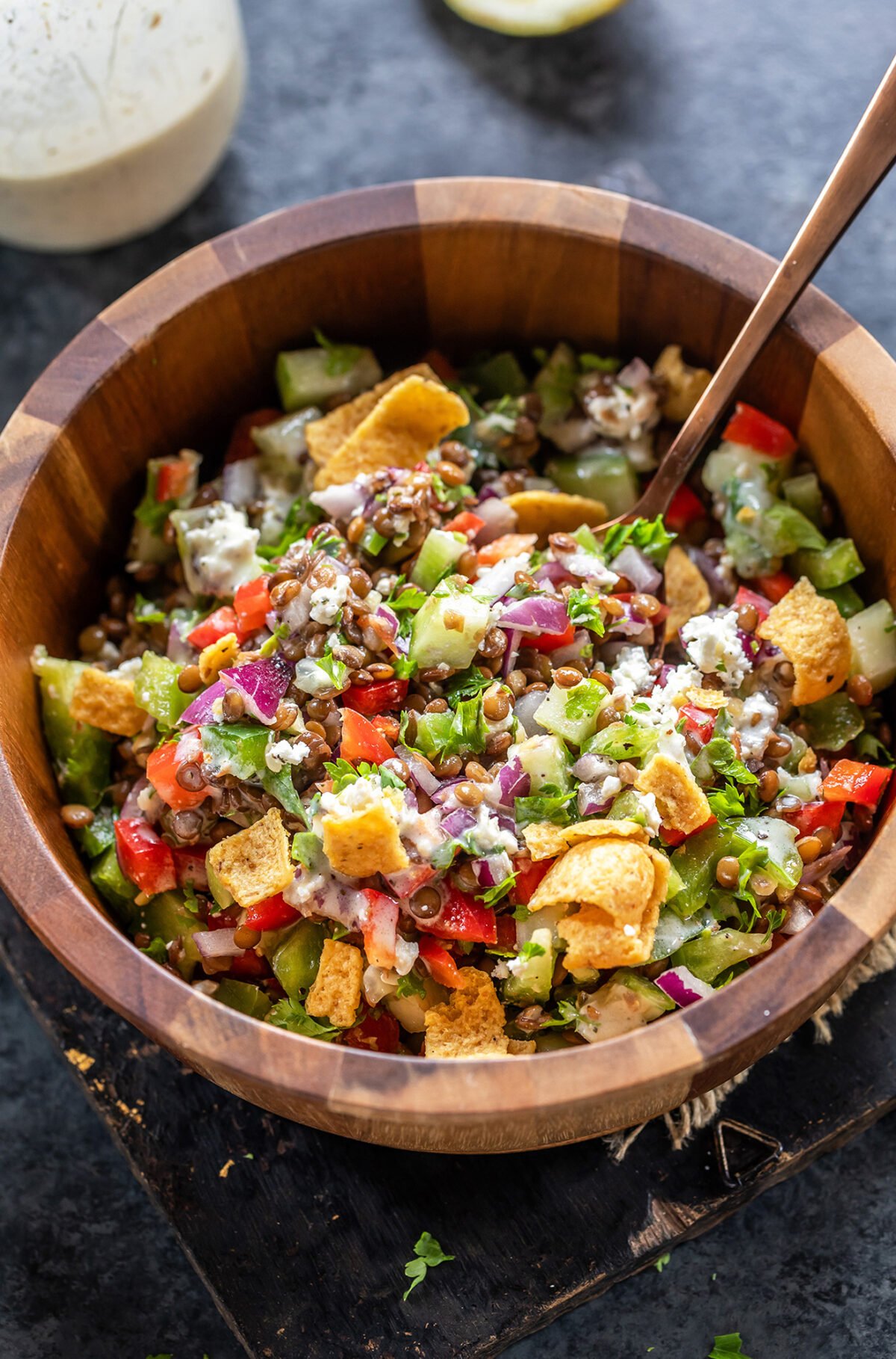 lentil salad with veggies served in a wooden bowl along with a spoon