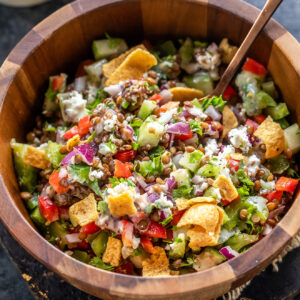 lentil salad with veggies served in a wooden bowl along with a spoon