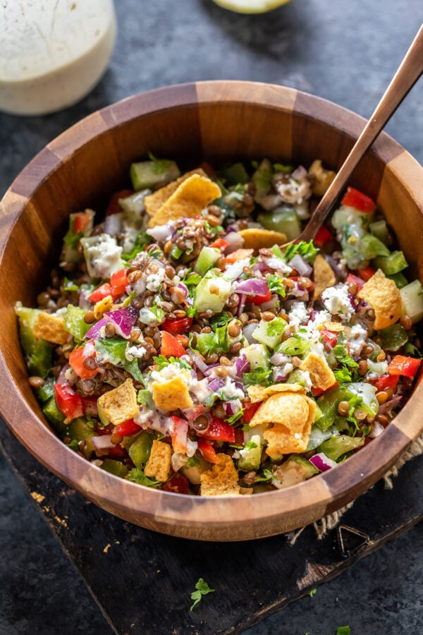 lentil salad with veggies served in a wooden bowl along with a spoon
