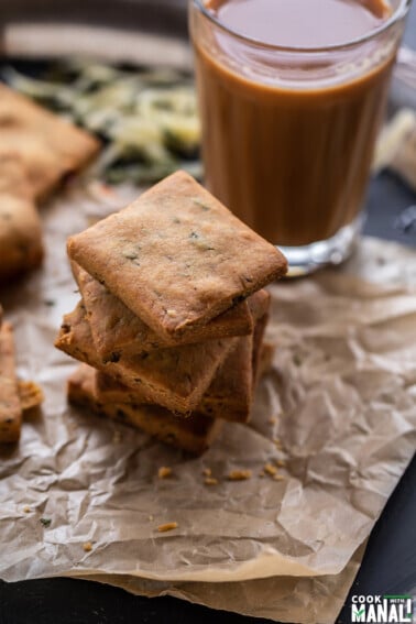 stack of cookies and a glass of chai placed in the background