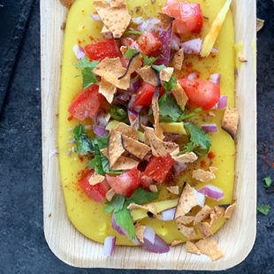 pureed moong dal topped with onion, tomatoes, cilantro, chilies and crushed papadum