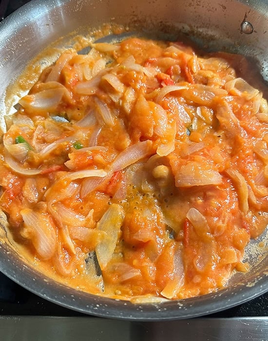 chopped onions and tomatoes getting cooked in a pan