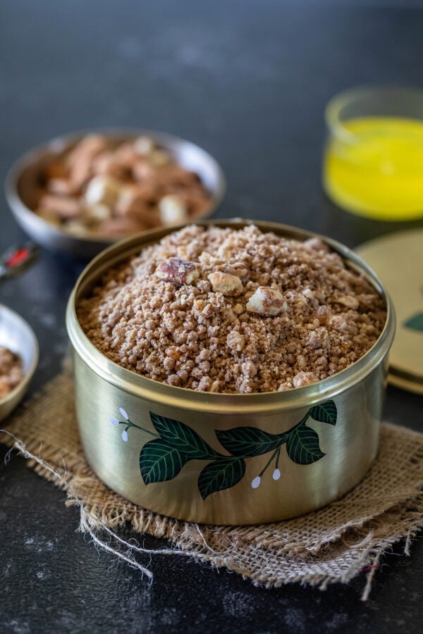panjiri in a brass box garnished with nuts and a bowl of ghee placed in the background