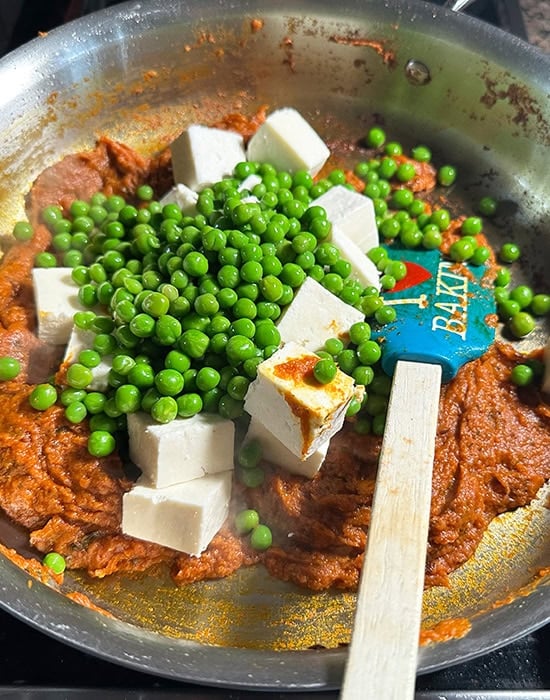 paneer and green peas being added to a curry