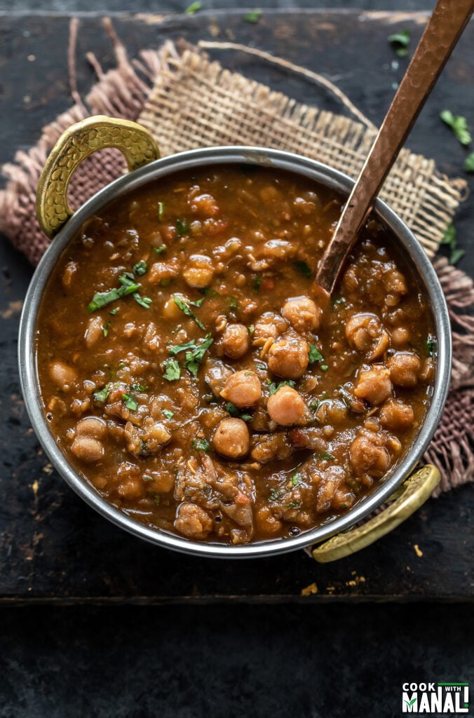 chole served in a copper kadai and garnished with cilantro