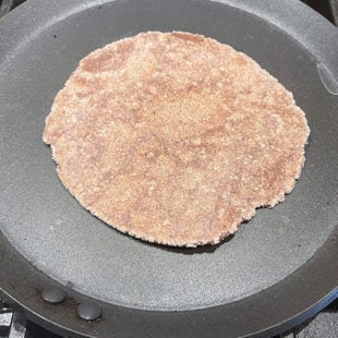rolled ragi roti placed on a tawa