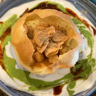 crisp fried ball of dough arranged on a plate with potatoes, chickpeas added to it