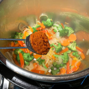 curry paste being added to a pot of veggies