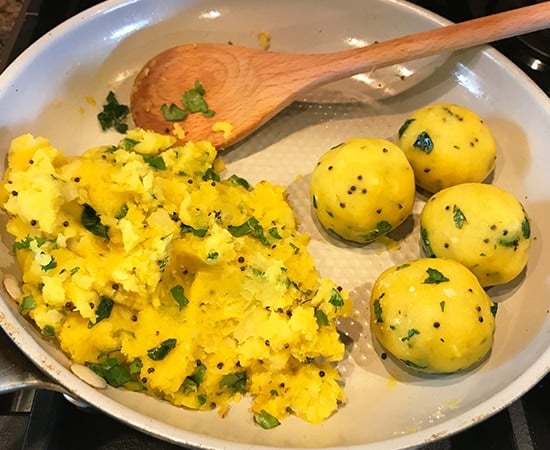 4 round mashed potato balls placed on a side in a pan with more mashed potatoes on side