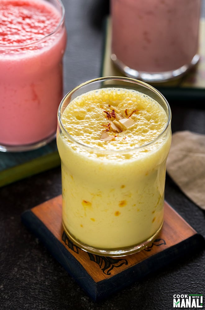 glass of saffron lassi on a coaster with more glasses of lassi in the background