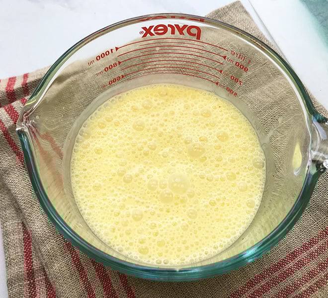 saffron lassi in a large measuring jar