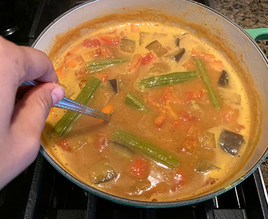 a spoon mixing dal and vegetables together