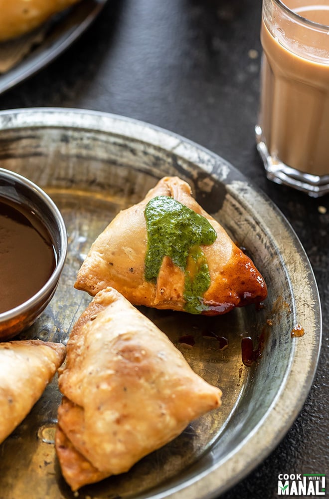samosa topped with green chutney and sweet chutney and placed in a plate