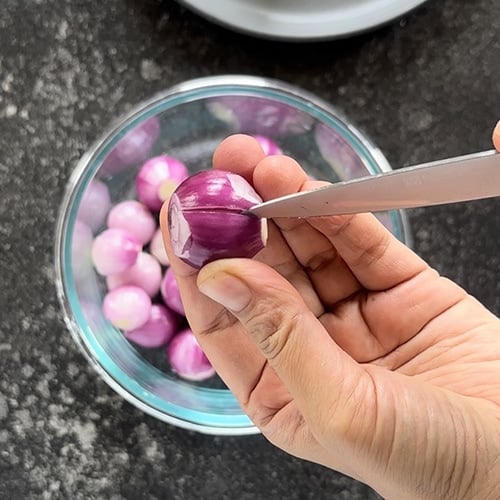 paring knife making a slit in pearl onion