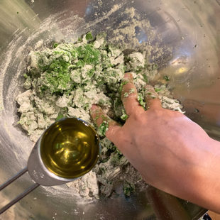 oil being added to a dough which is being mixed by a pair of hands