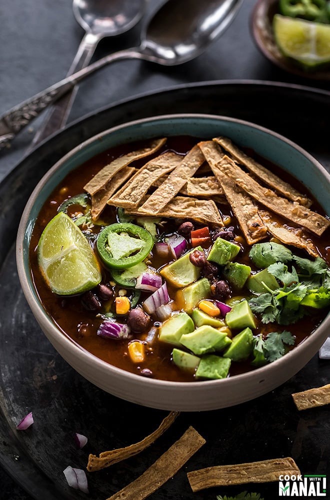 instant pot vegetarian tortilla soup in a bowl topped with tortilla strips, avocado, cilantro, lime wedge and jalapenos