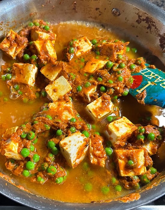 paneer, peas with spices and water in a steel pan